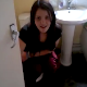 A brunette girl is video-recorded taking a shit while sitting on a toilet. There are no audible pooping sounds. The girl chases the videographer out of the bathroom, but the video continues through the bathroom window.